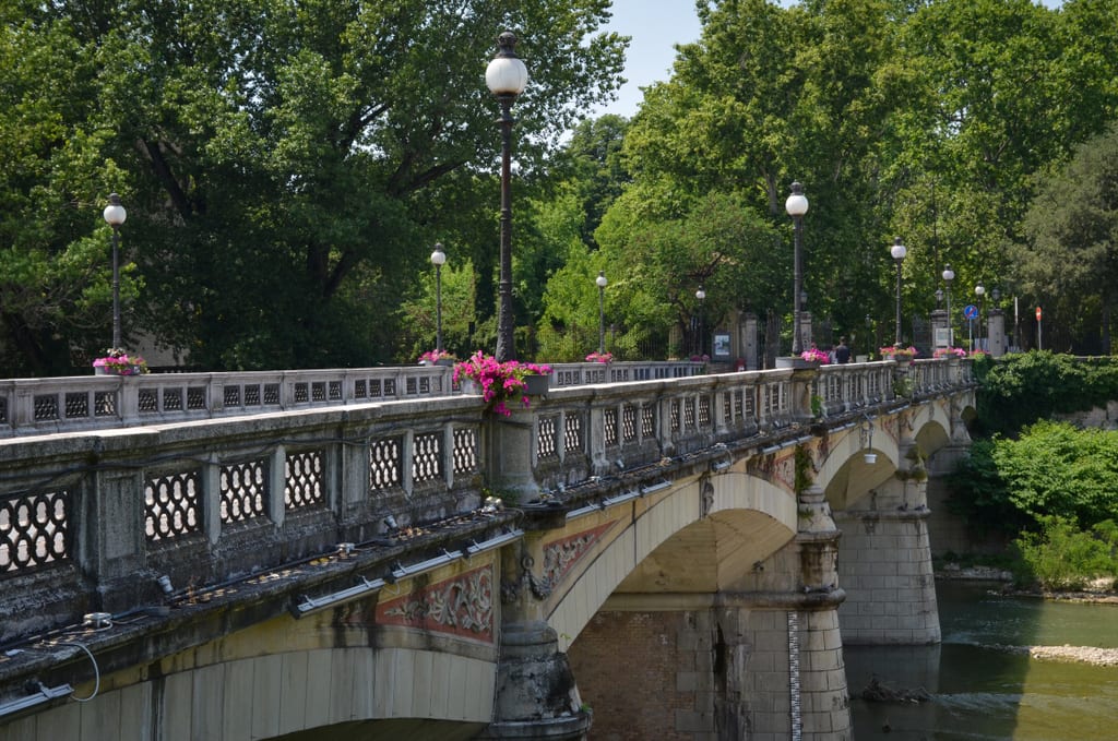 The Verdi bridge in Parma, gray stone and iron, topped with pink flowers.