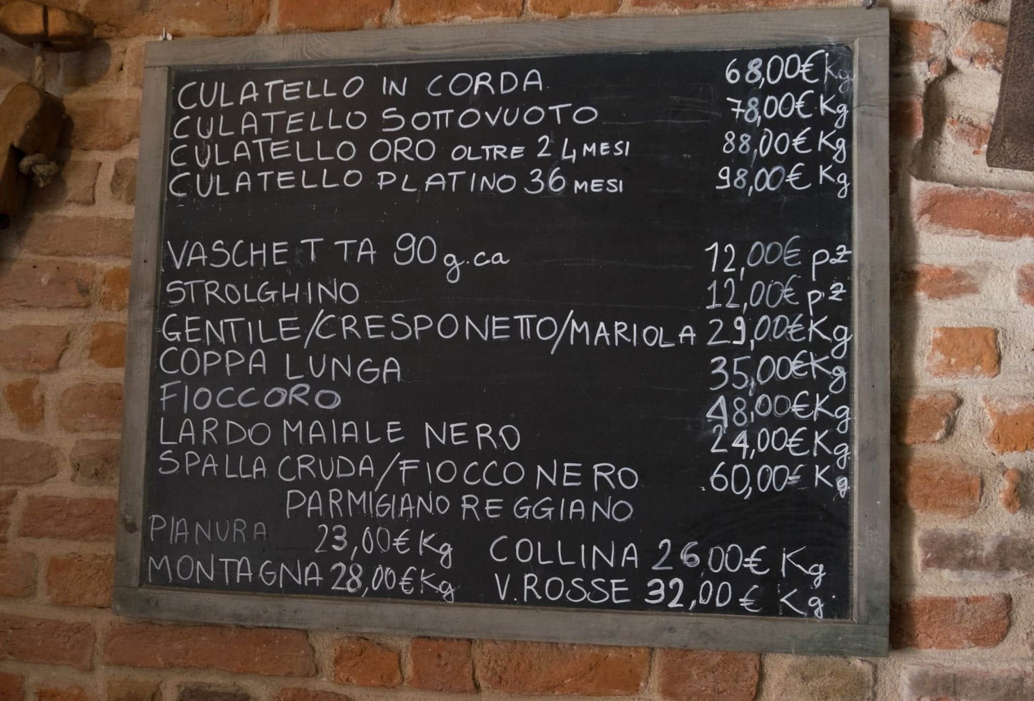 A blackboard with the prices of culatello written on them, starting at 68 euros per kilogram.