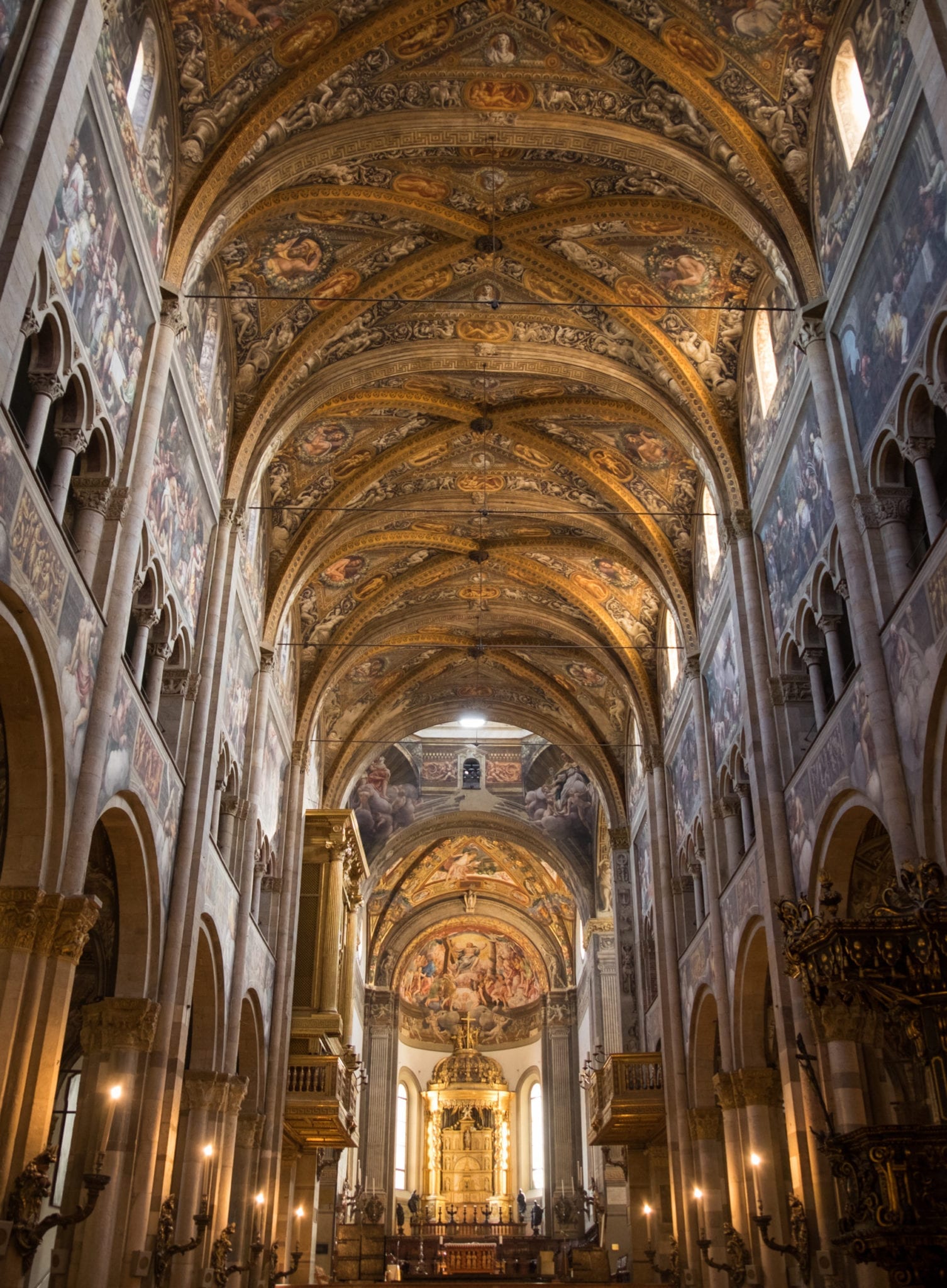 Parma's cathedral, leading back to the altar, each wall covered with paintings and ornate gold decoration.