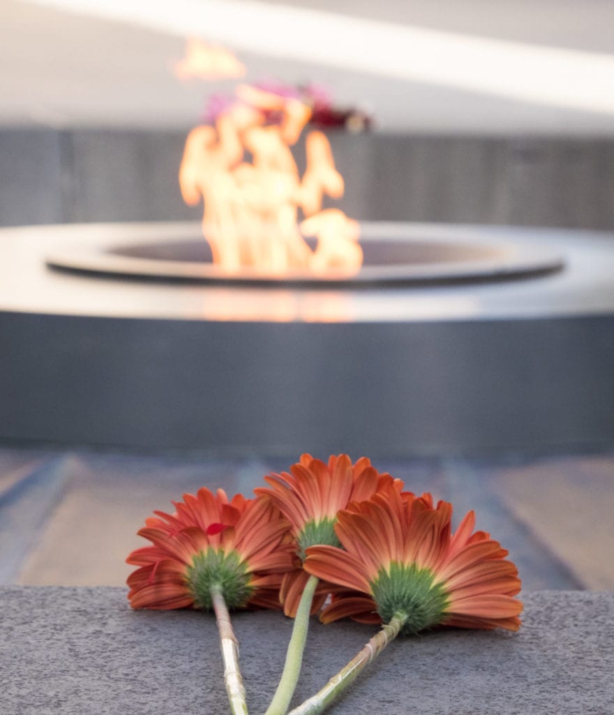 Three red flowers resting in front of the eternal flame at the Armenian Genocide Memorial.