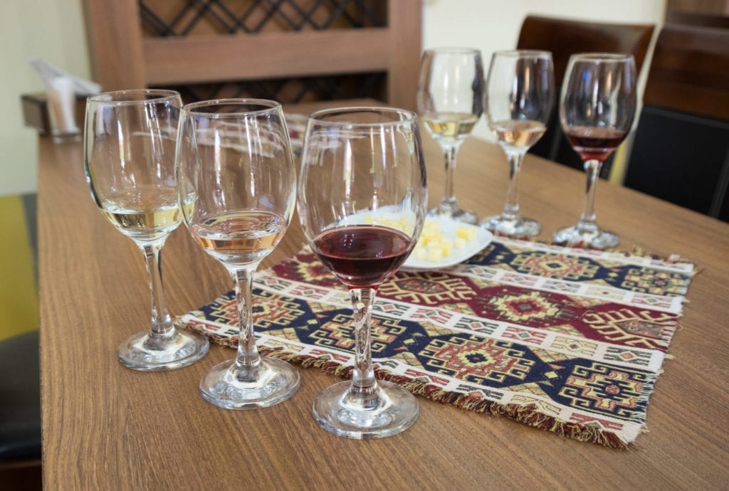 Six wine glasses surrounding a traditional Armenian patterned placemat.