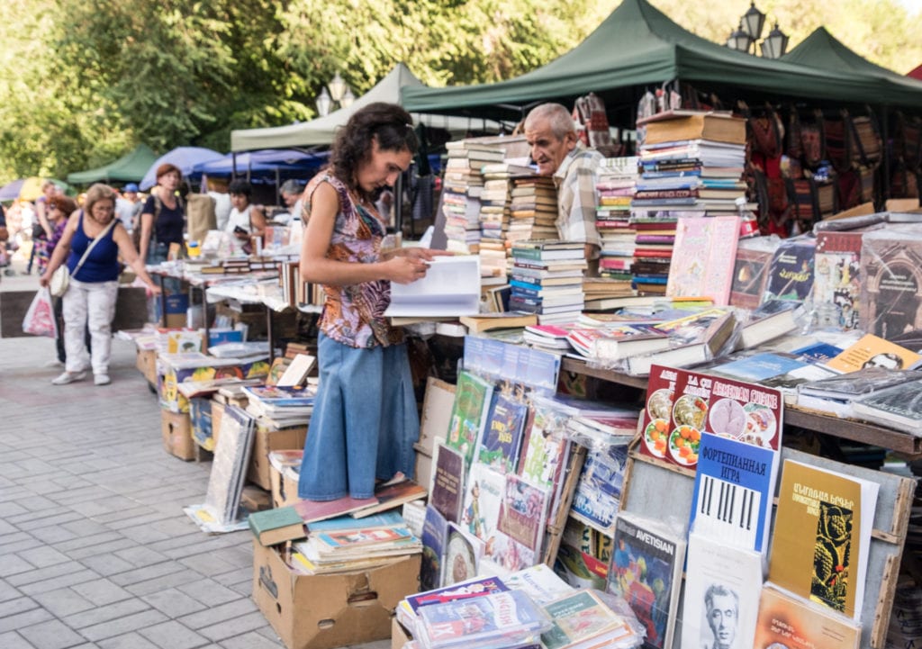 A woman peruses books on a table at an outdoor market in Yerevan.