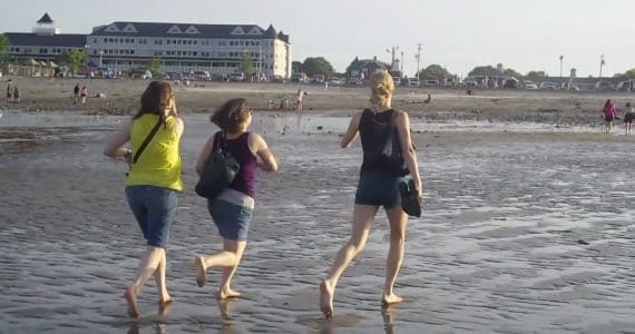 Three young women running down the beach in York Maine.