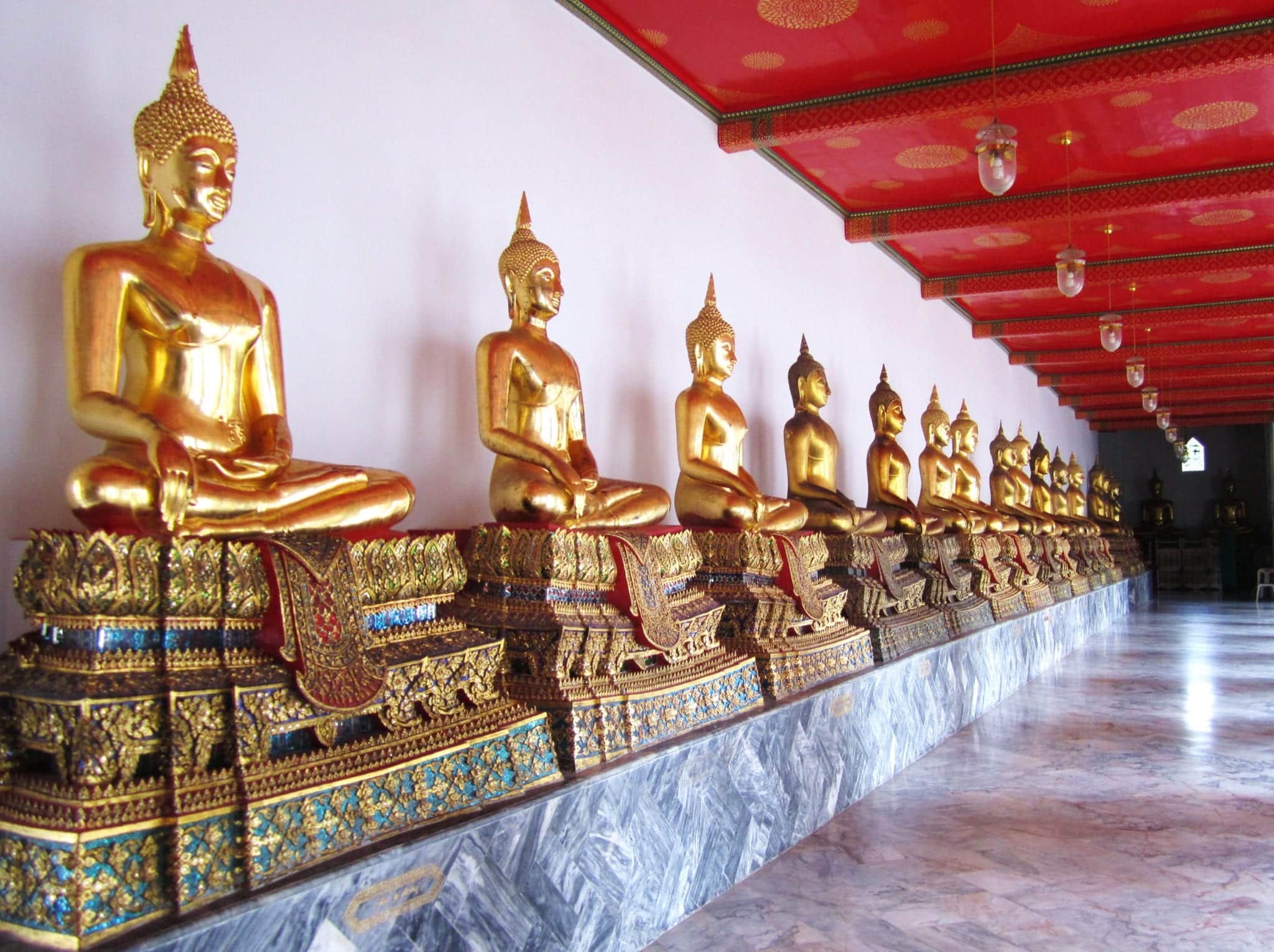 A long row of Golden Buddhas lined up seated cross-legged at Bangkok's Wat Pho.