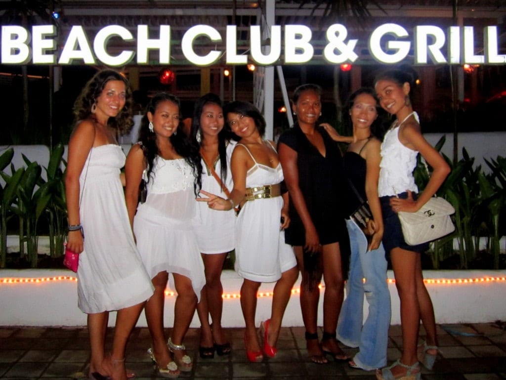 Kate and several Indonesian girlfriends, most dressed in white dresses, at a beach party labeled BEACH CLUB AND GRILL.