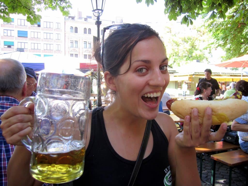 Kate holding a liter beer and eating a sausage.