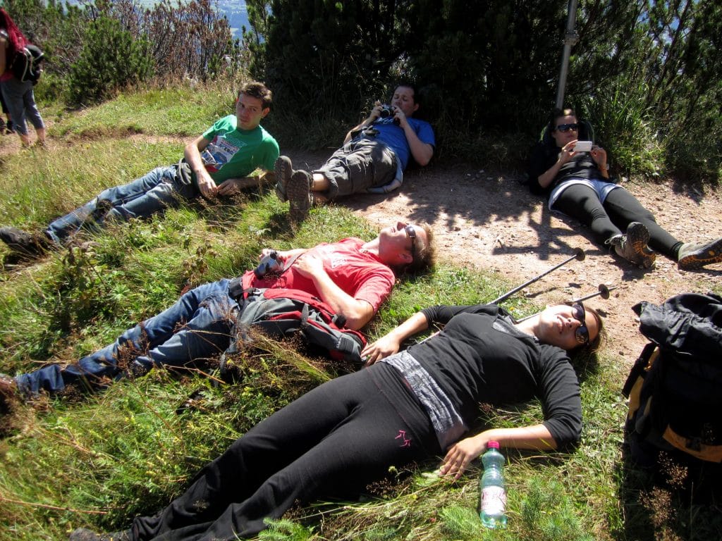 Five friends lying on the grass to recover from a tough hike.