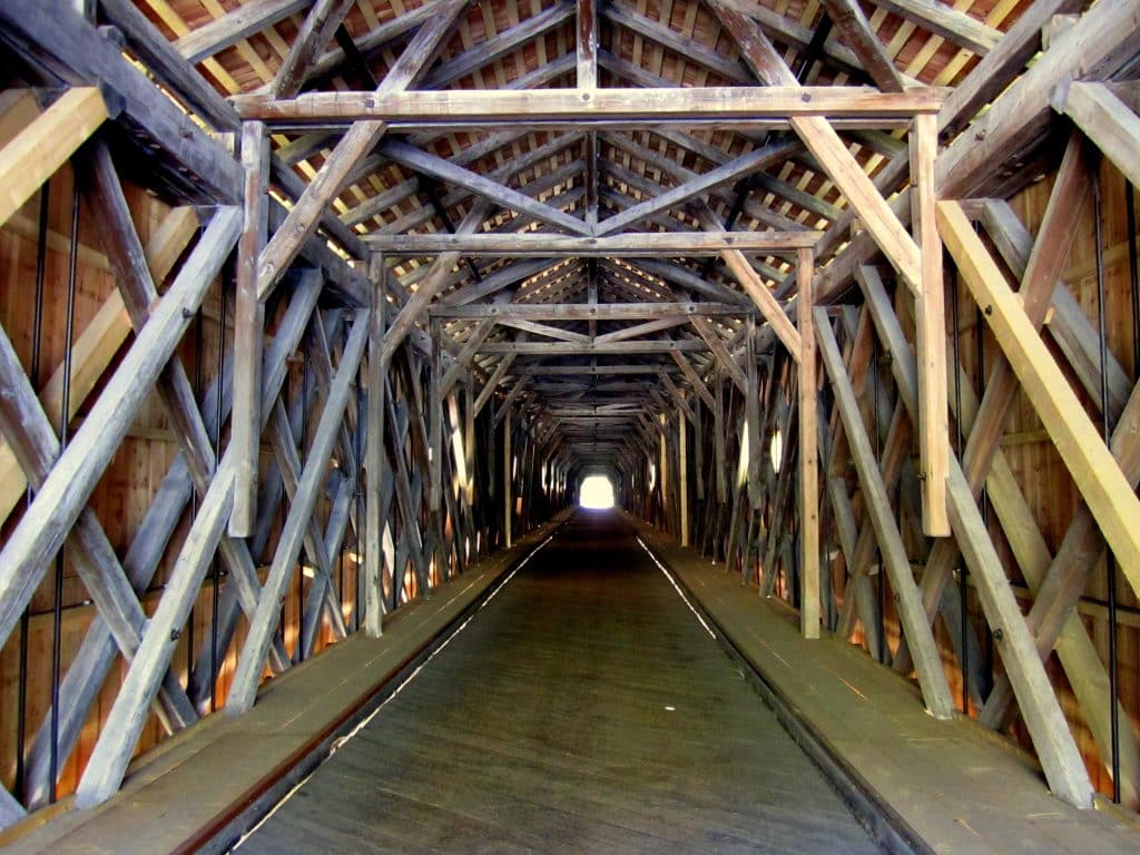 Looking straight through a covered bridge with lots of beams at different angles.
