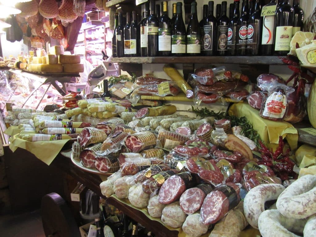 A food market in Bologna with shelves crammed with meats, cheeses, and olive oils.
