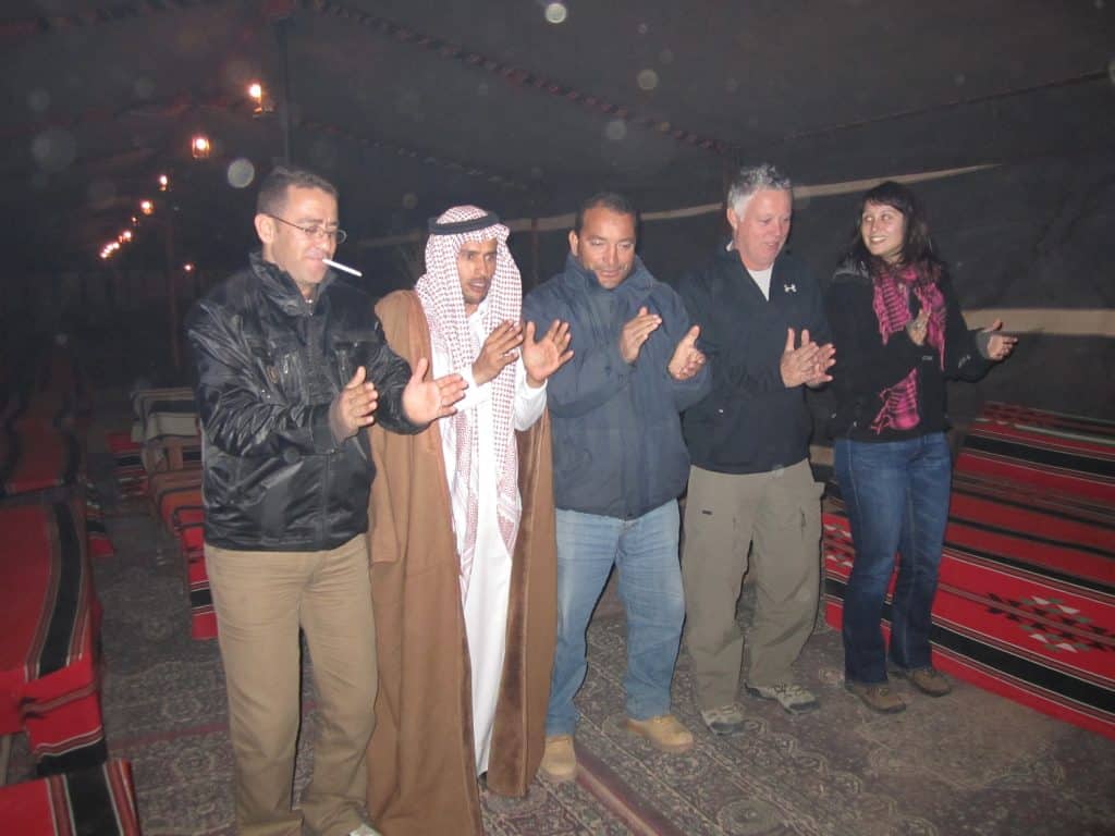 A group of Bedouins and Westerners clapping their hands to a song