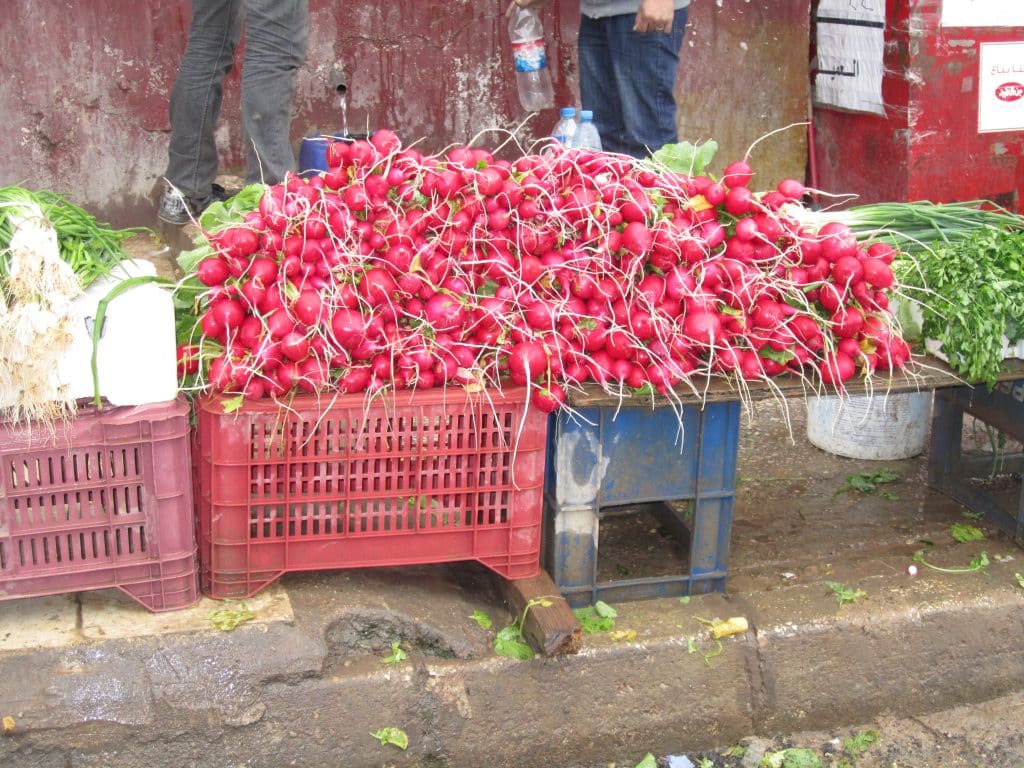 An enormous pile of bright red radishes on a street cart.