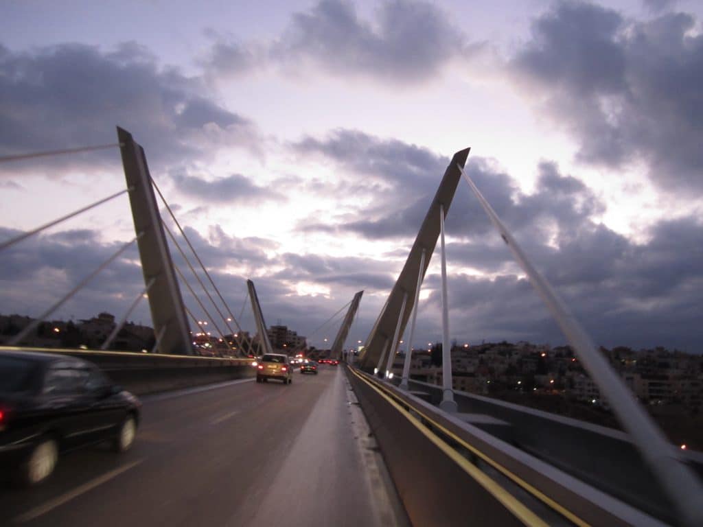 A suspension bridge in Jordan set against a cloudy purple sky