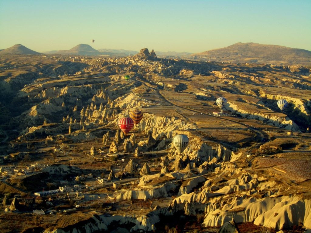Hot air balloons flying over the jagged landscape of Cappadocia, Turkey.
