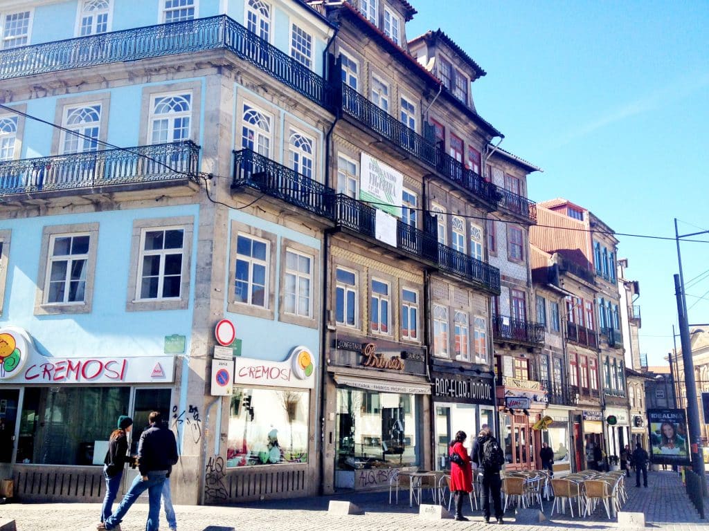 A city block with lots of weary-looking gray buildings with wrought iron balconies
