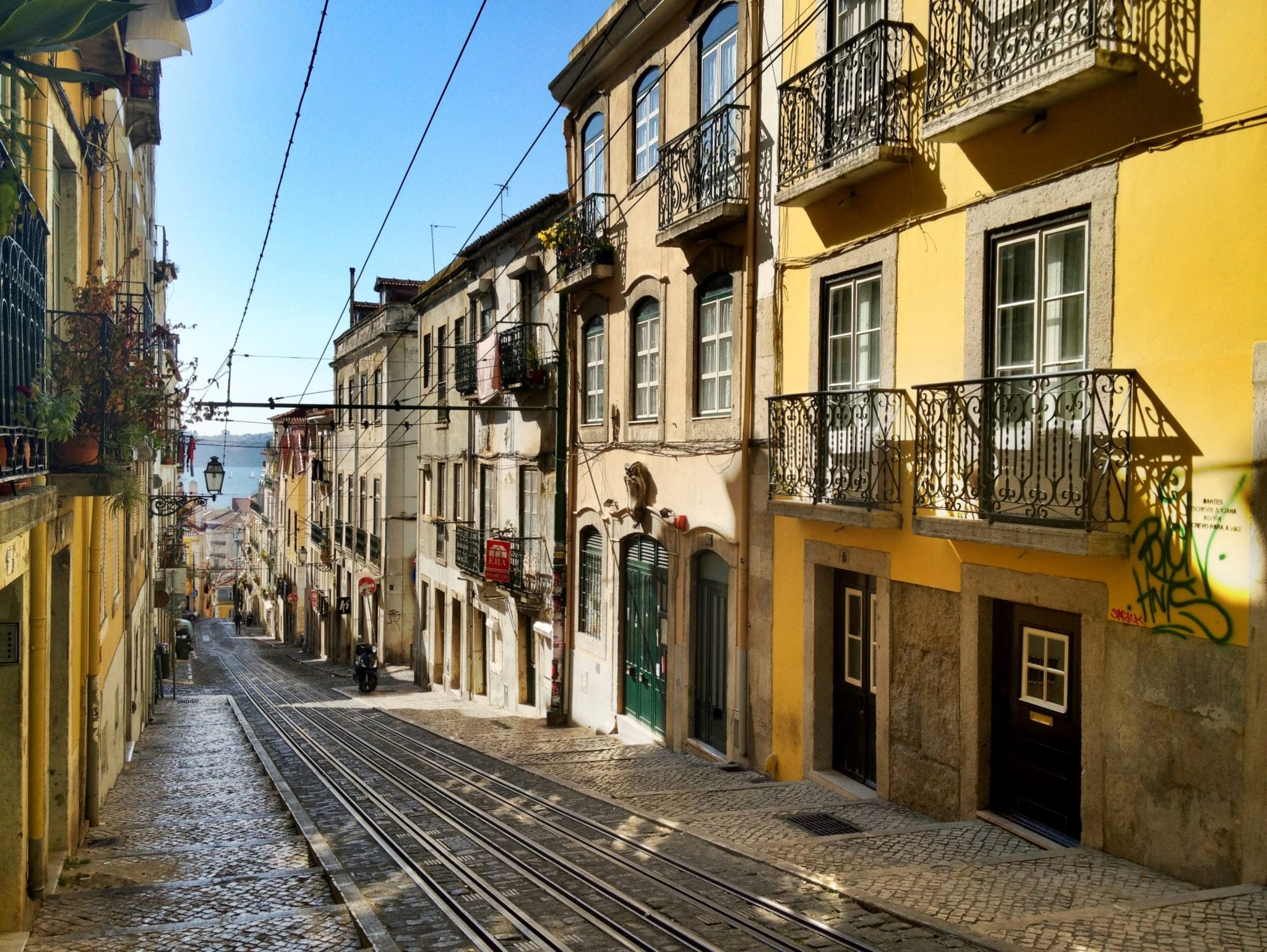 Buildings line a cobblestone street with cabel car tracks.