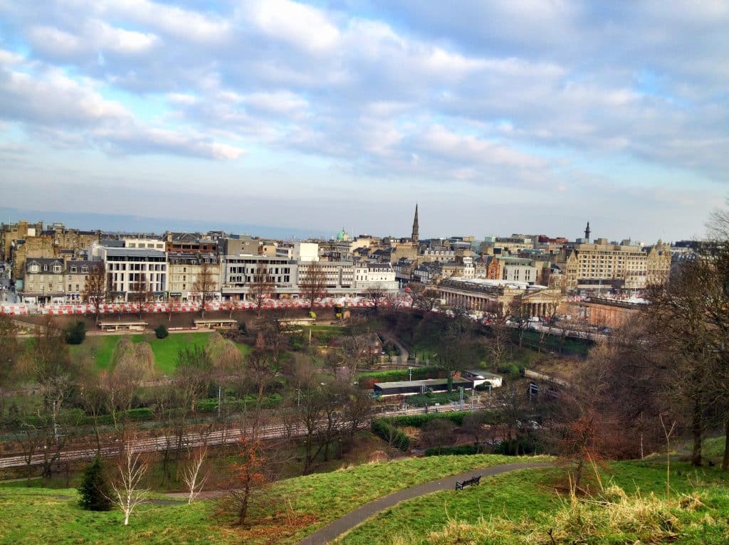 The city skyline of Edinburgh underneath a sky with white and purple clouds.