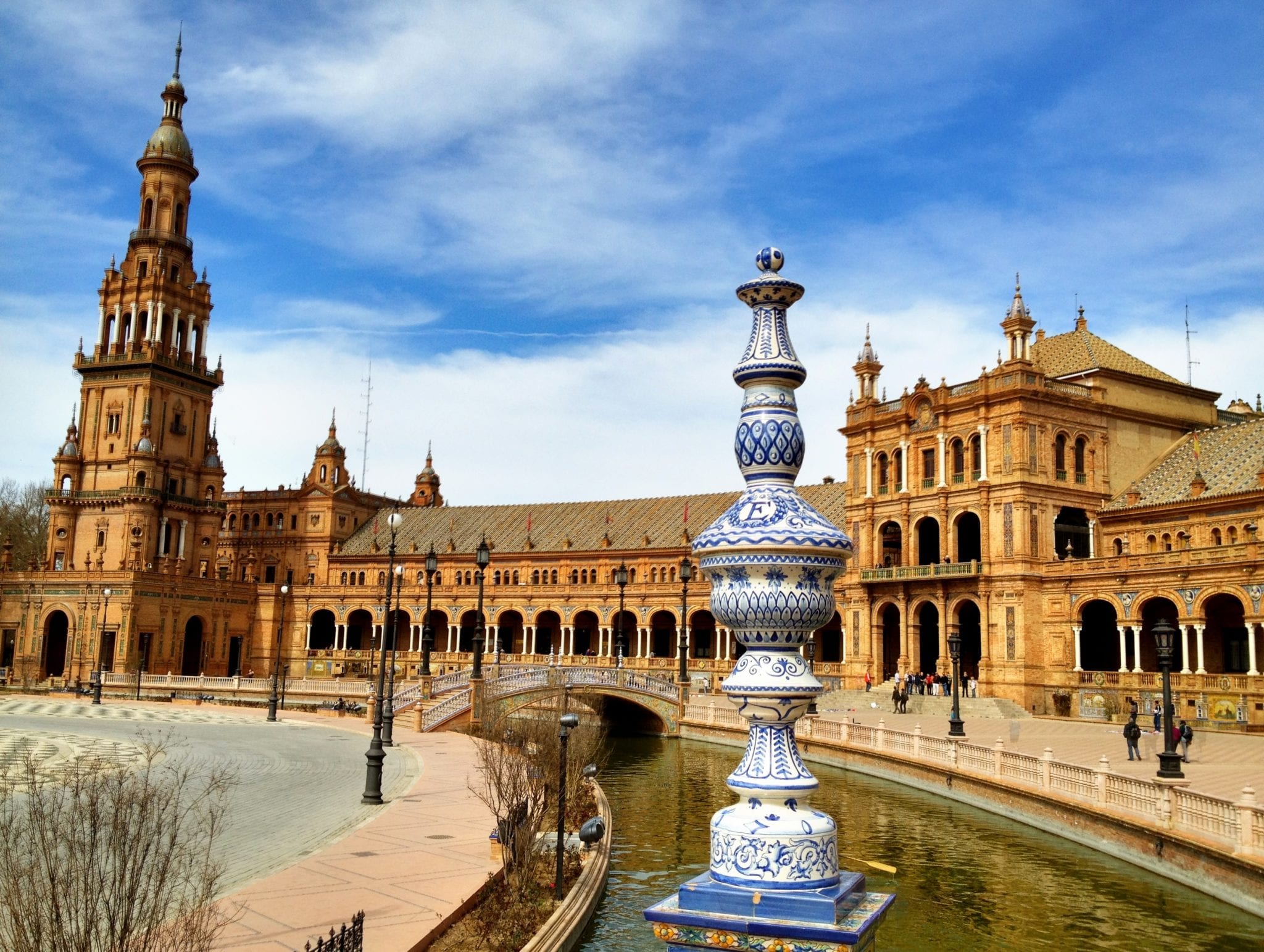 Canal and bridge flanked by building with beautiful Spanish architecture.