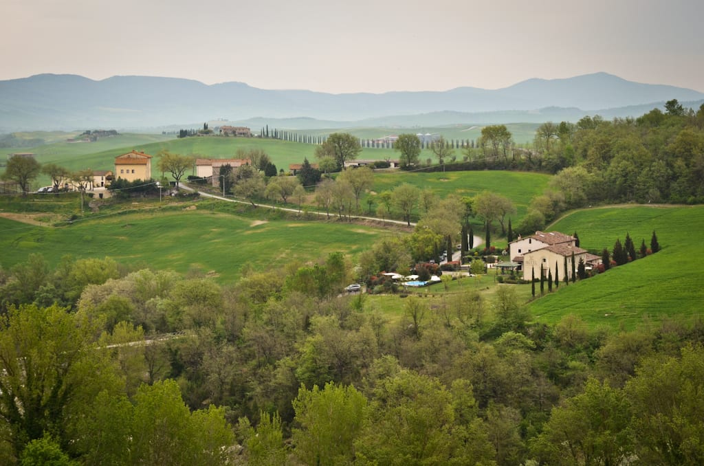 Aerial view of rolling hills in the Tuscan countryside, with mountains off in the distance