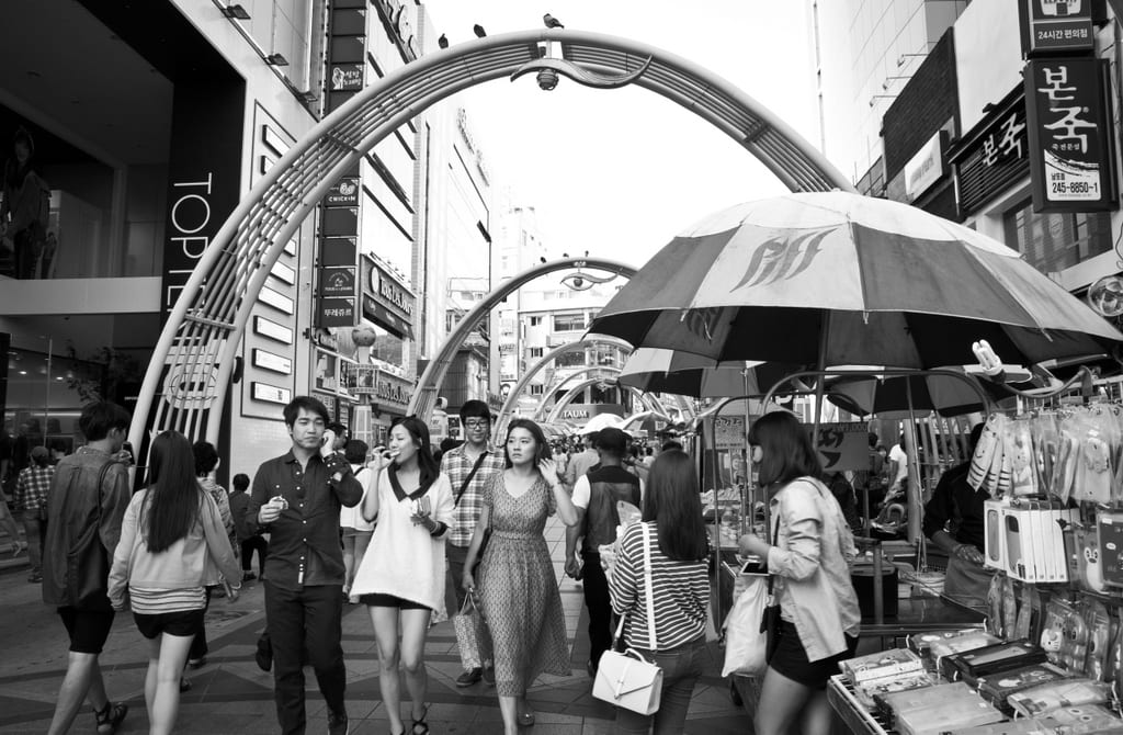 A black and white shot of people shopping on a street in Busan, Korea