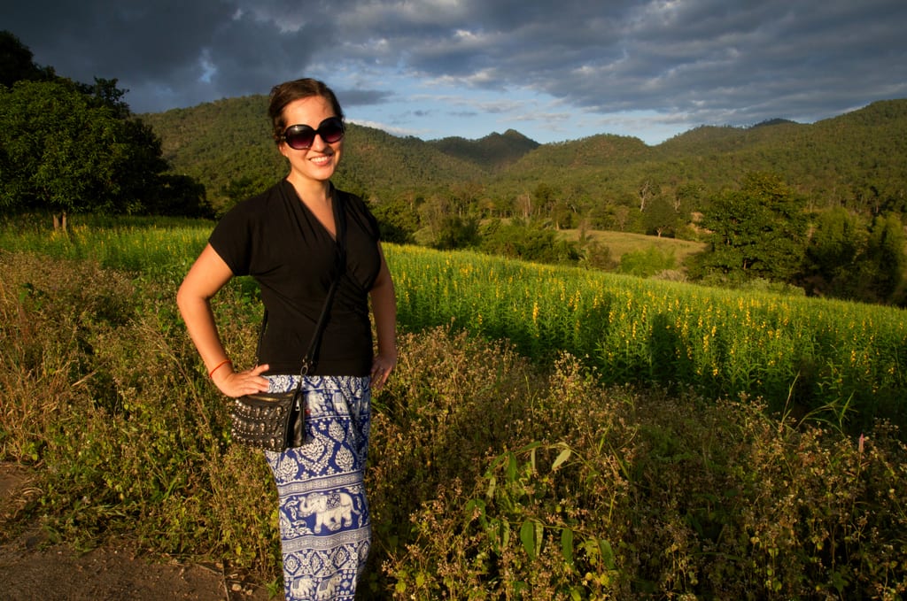 Kate wearing elephant-printed pants and standing in front of a mountainous green overview in aPi, Thailand.