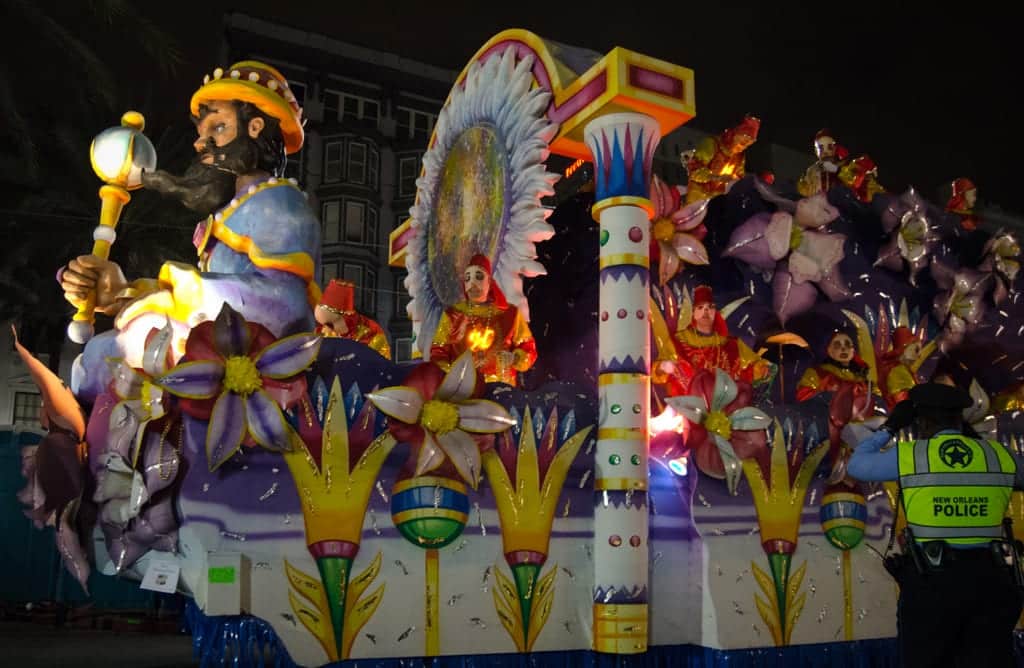 A big colorful float with flower patterns made out of cardboard on a Mardi Gras parade.