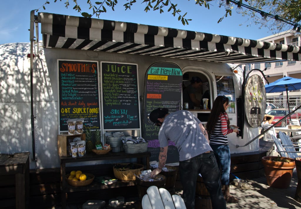 A silver Airstream trailer turned into a food truck selling smoothies and juices.
