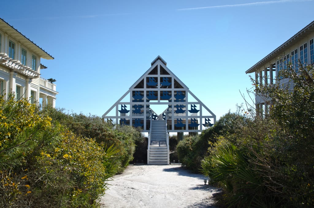 A triangular blue and gray wooden building on the edge of the beach.