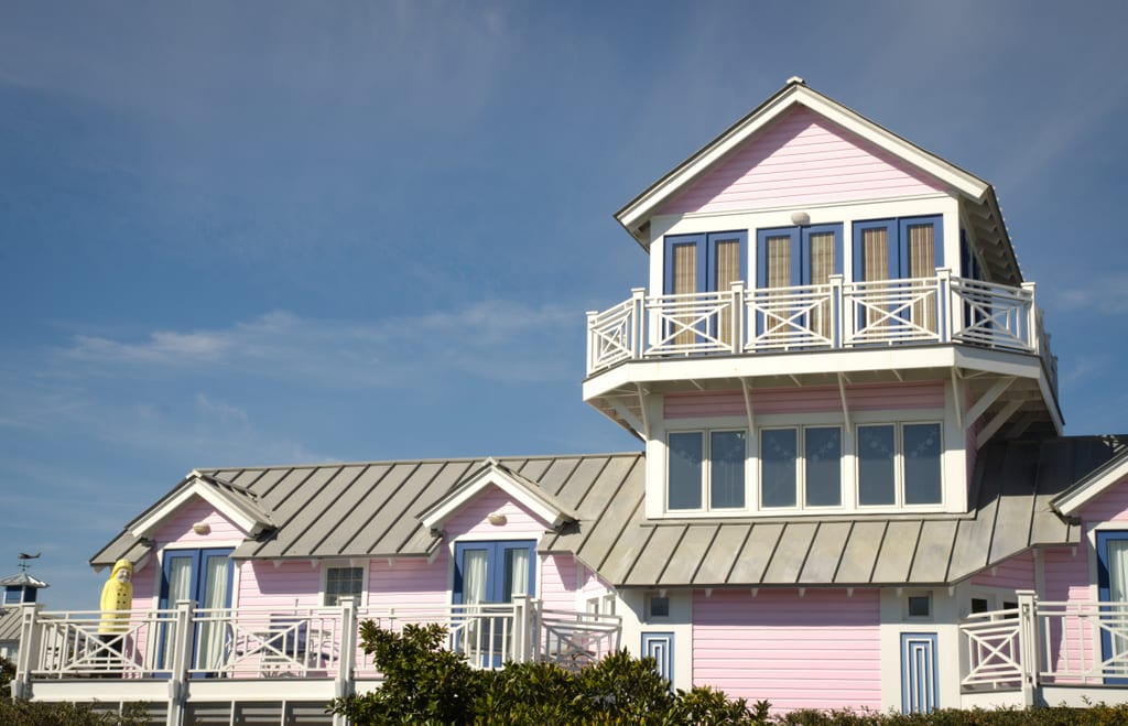 A pink house with purple trim and white balconies and porches.