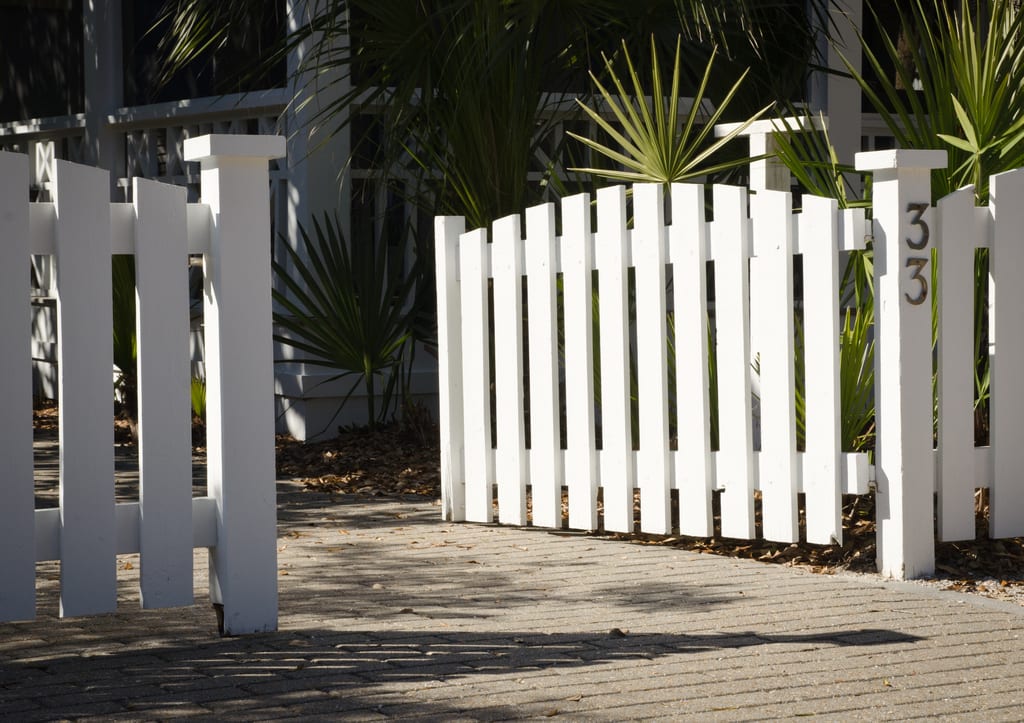 A white picket gate open on a driveway.