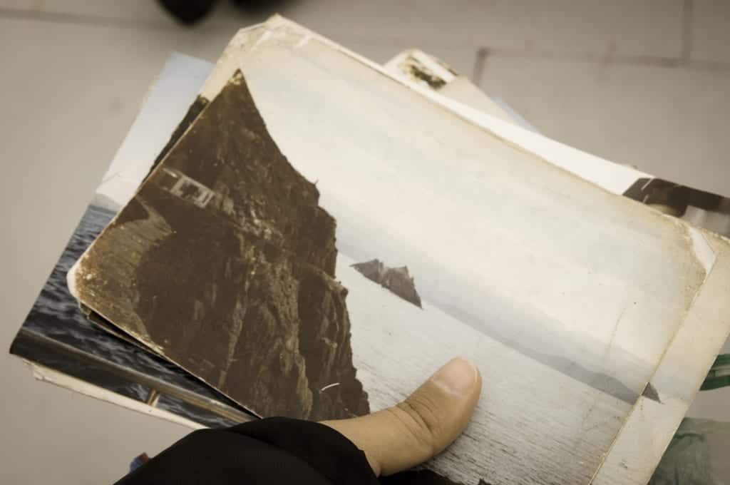 A hand holding old photos from Skellig Michael taken in the 1970s.