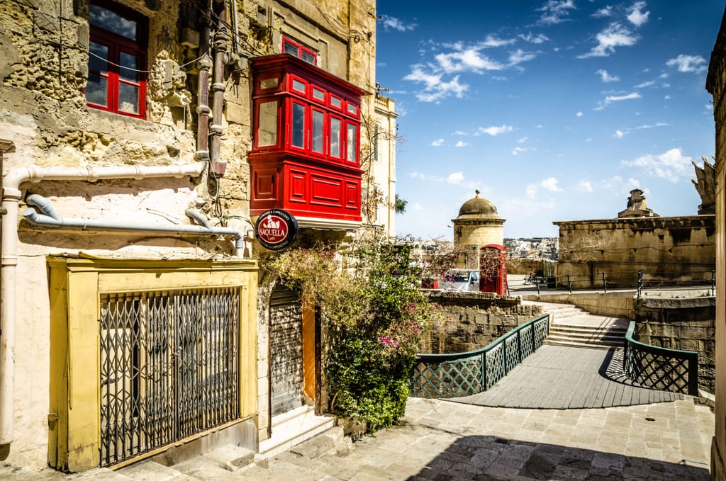 Walkway in front of building with red window frame.