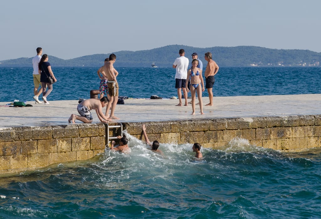 Boys swimming in the waves off a dock in Zadar, Croatia