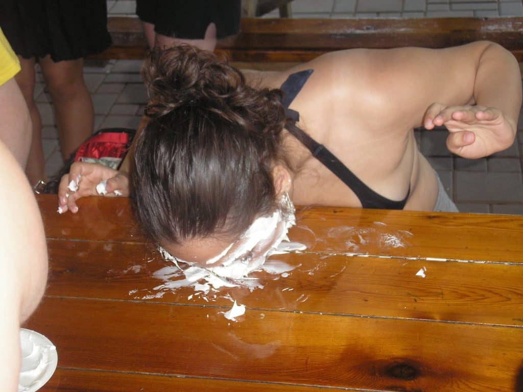 Kate with her head in a pie full of whipped cream.