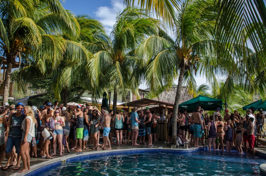 Partiers clustered around a pool, surrounded by palm trees, at Sunday Funday in San Juan del Sur, Nicaragua