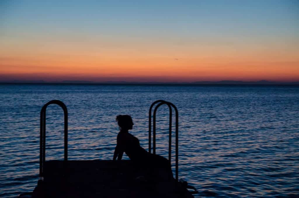 A silhouette of Kate against the blue lake and a red-to-blue sunset behind her.