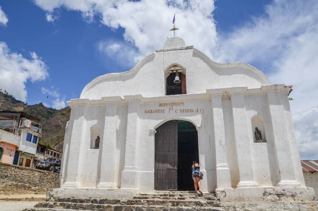 A woman peeks into a bright white church.