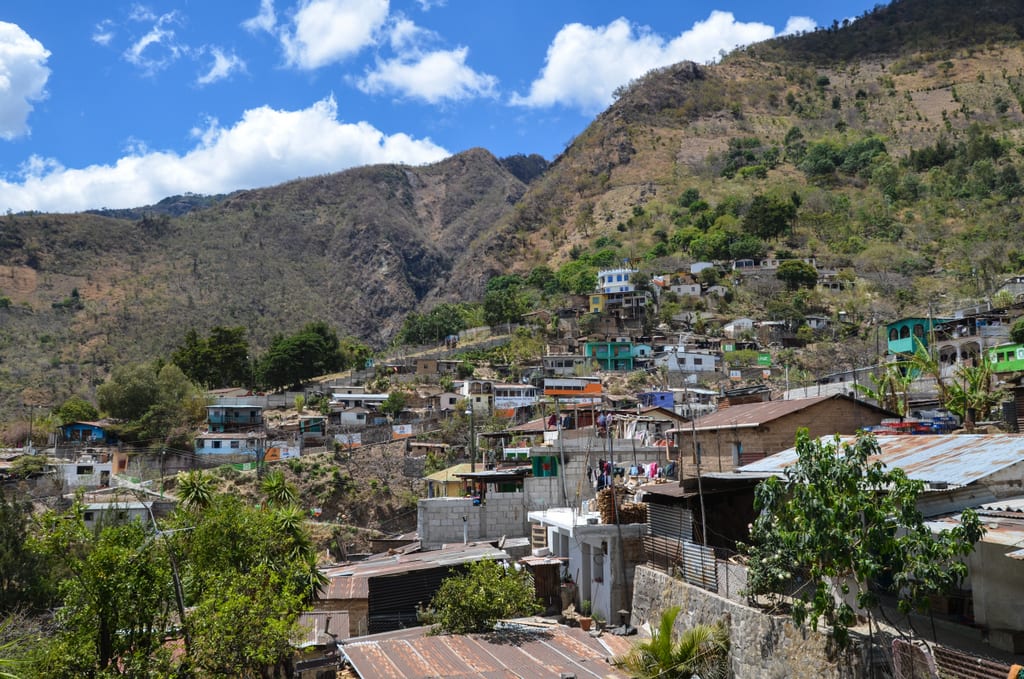 A hilly village set against a mountain, with buildings of stone and metal.