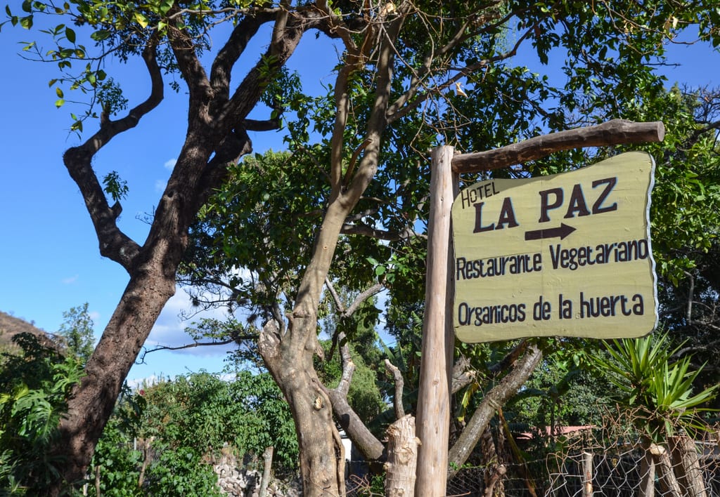 A sign reading La Paz Restaurante Vegetariano, set against trees.