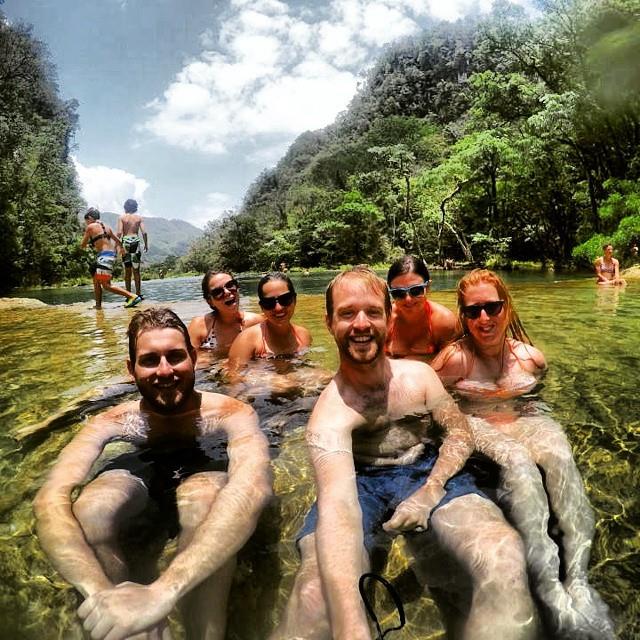A group of Kate and five friends sitting in the clear green water, grinning for a selfie.
