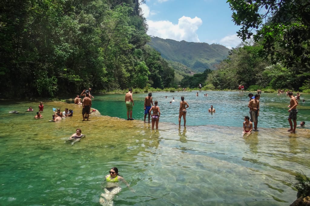 People standing at one of the turquoise pools at Semuc Champey