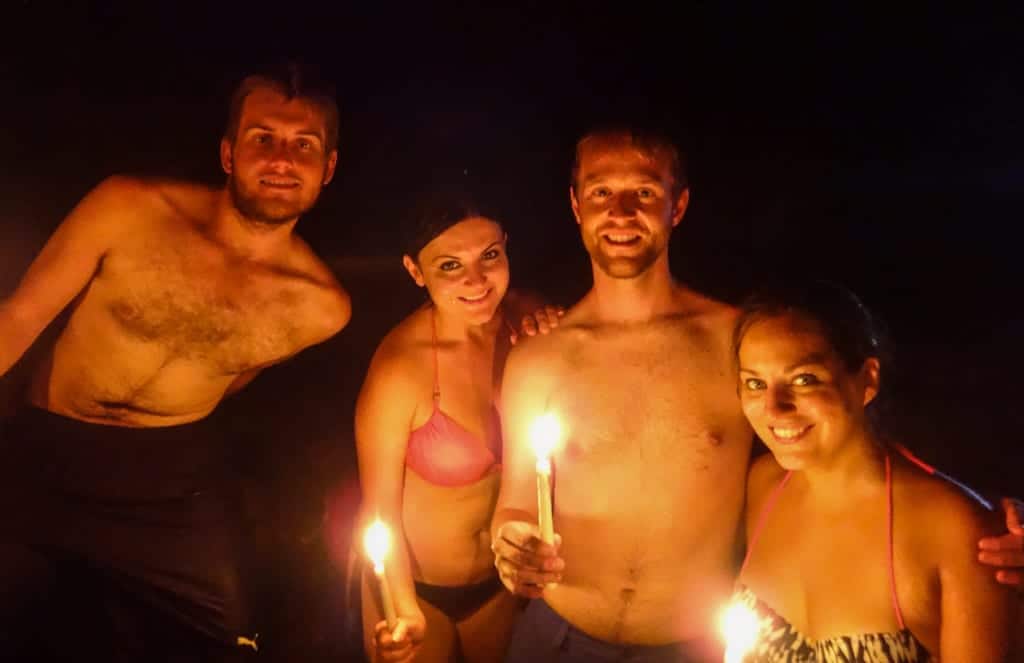 Paul, Erisa, Shaun, and Kate standing in a cave and holding candles.