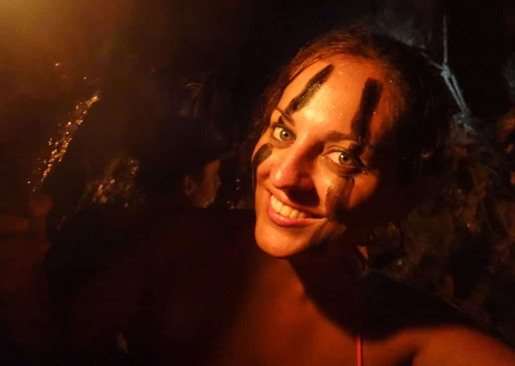 Kate smiles devilishly at the camera, a streak of black paint down each side of her face.