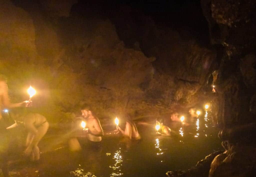 People walking through the water in Semuc Champey Caves with candles in hand.