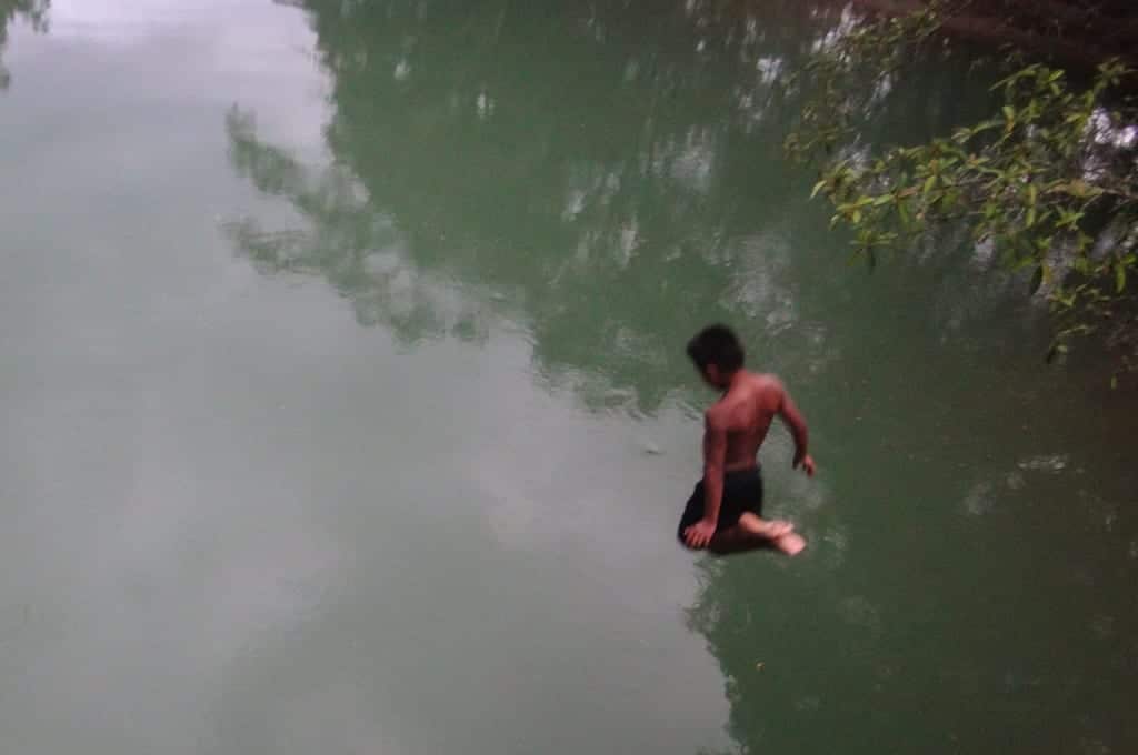 A kid jumping into the water from way above.