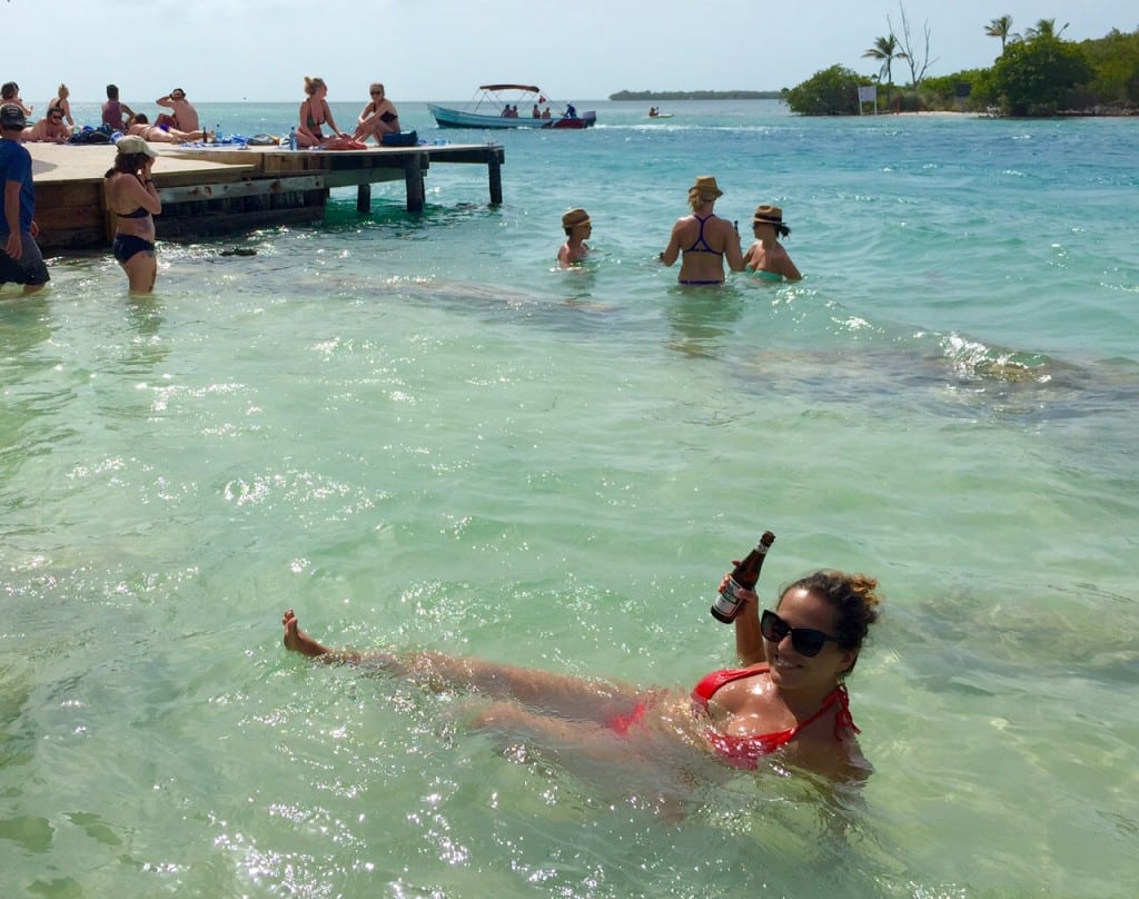 Kate swimming in the clear water at Caye Caulker with a beer in one hand