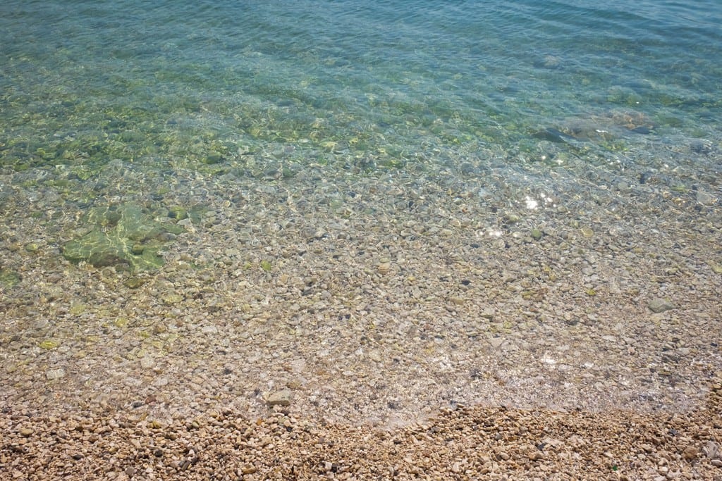 Clear turquoise water and a pebble beach.