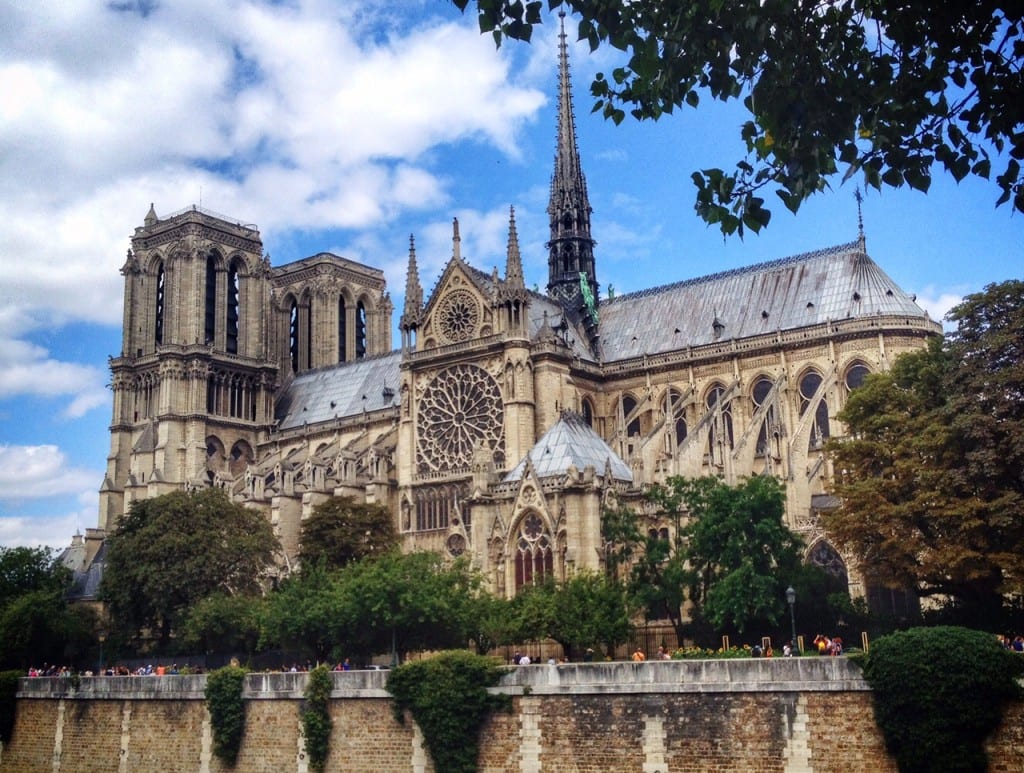 Notre Dame Cathedral, all gothic with towers and lit up behind a blue sky.