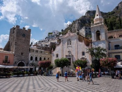 A piazza in Taormina with a church and black and white chess board-like tiles on the square.