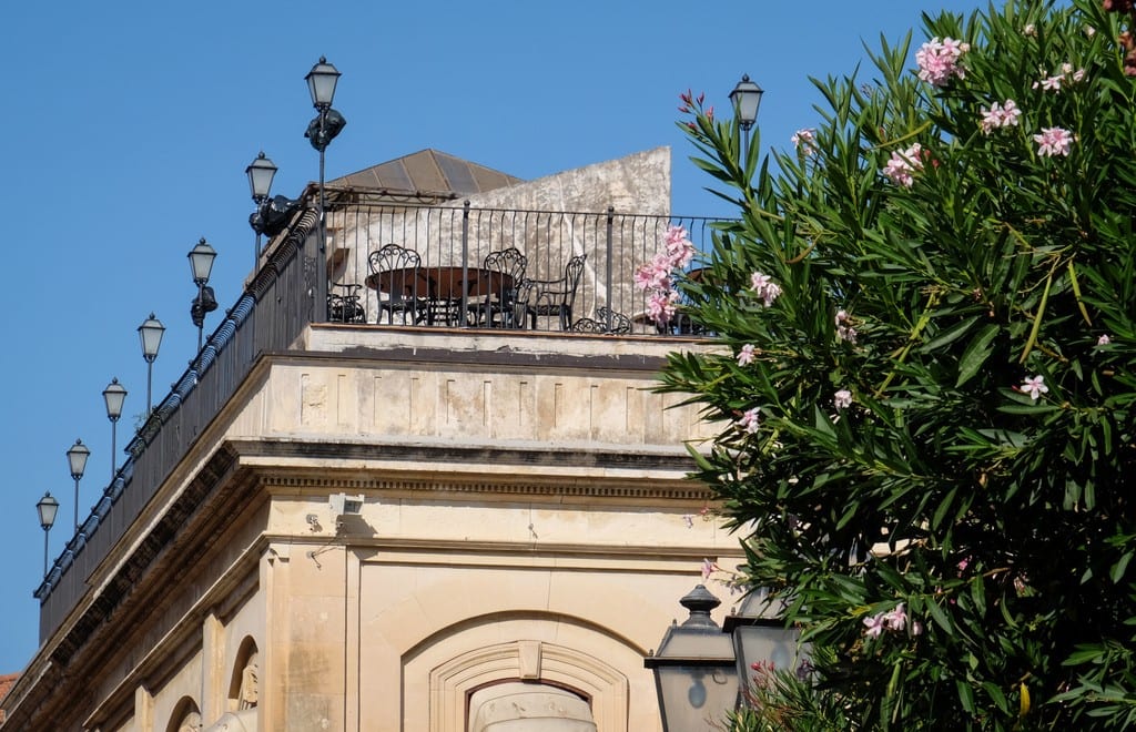 A rooftop cafe in Taormina, shot from below. Lamps are on the edge of the building.