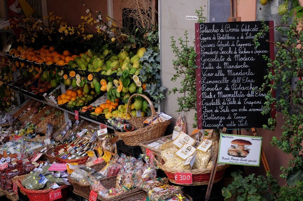 A shop in Taormina with lots of fruit for sale, and a chalkboard with daily menu specials on it.